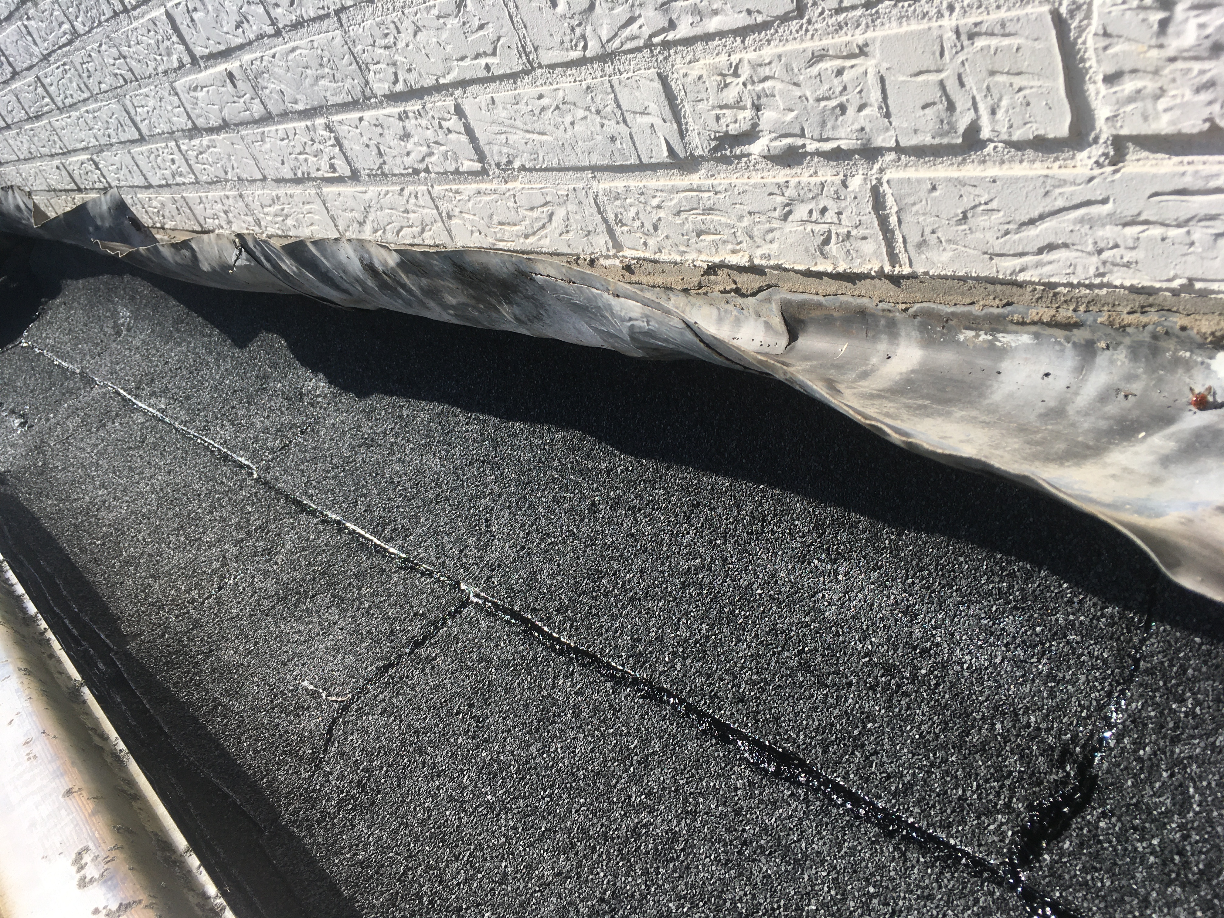 Tijdens: strakke bitumen detaillering ter plaatse van de gevel, het oude lood is behouden als geveldetaillering.